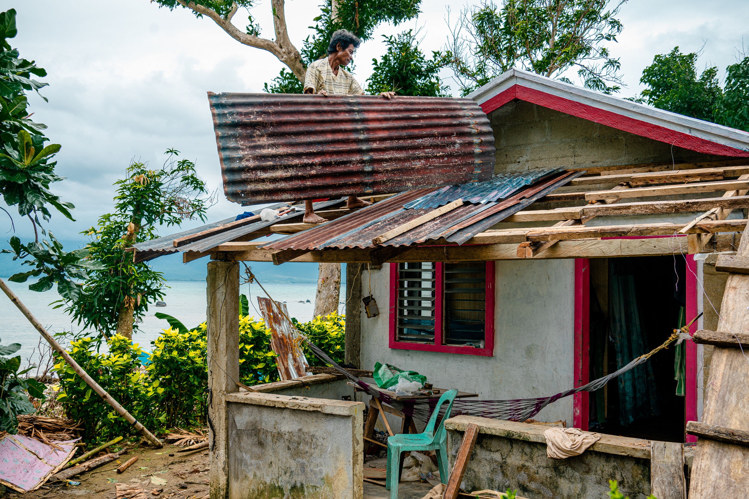 A man repairs his roof after receiving support from UN Central Emergency Response Fund (UNCERF) following Super Typhoon Rolly. In 2020, a series of typhoons hit the Philippines, destroying people’s homes and livelihoods. Photo: IOM/Andrea Empamano